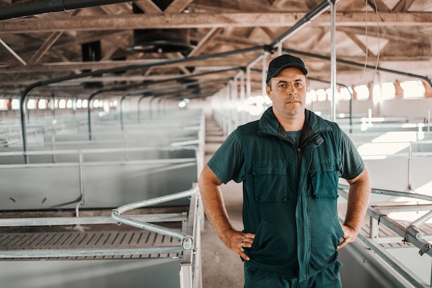 Farmer standing in empty barn with hands on hips