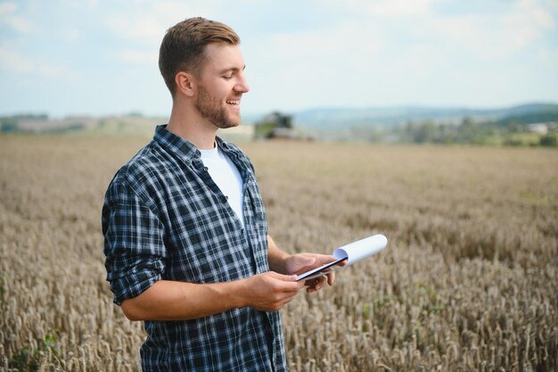 Contadino in piedi nel campo di grano al raccolto