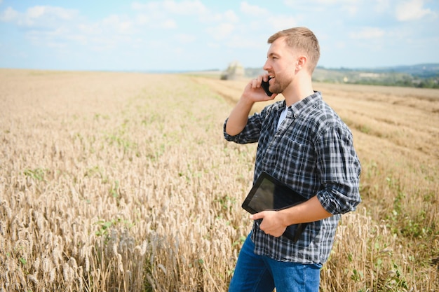 Contadino in piedi nel campo di grano al raccolto