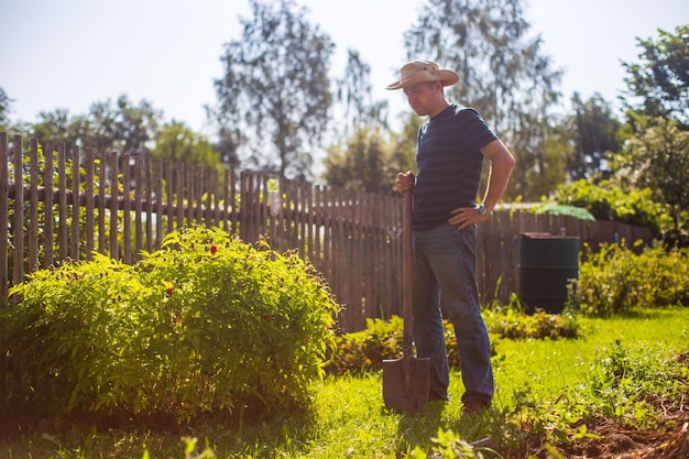 The farmer stands with a shovel in the garden Preparing the soil for planting vegetables Gardening concept Agricultural work on the plantation
