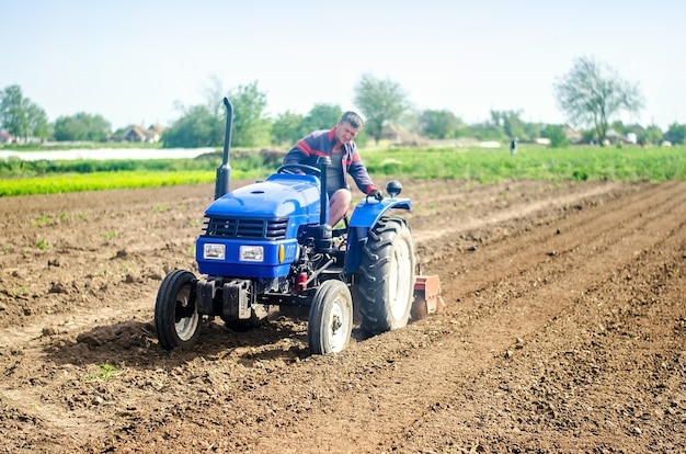 A farmer on a tractor cultivates a farm field Soil milling crumbling and mixing