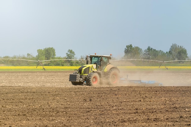 Farmer in tractor preparing land seedbed cultivator. Agriculture tractor landscape.