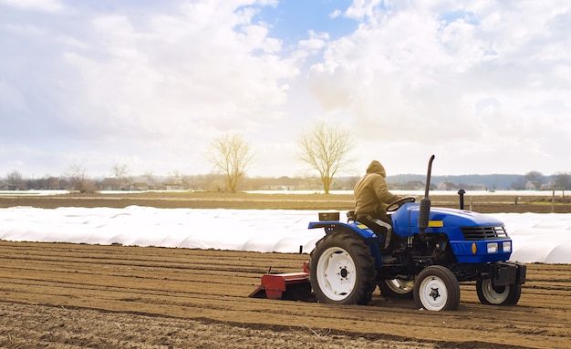 Farmer on a tractor with milling machine loosens grinds and mixes soil