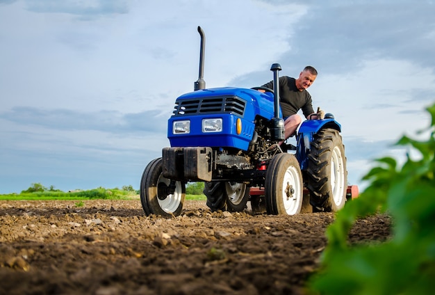 Un agricoltore su un trattore lavora nel campo fresatura del terreno frantumazione e allentamento del terreno