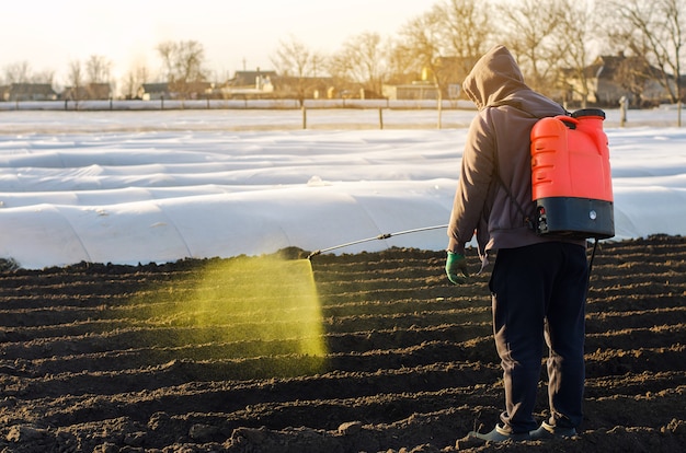 The farmer treats the field from weeds and grass for growing potatoes Use chemicals in agriculture