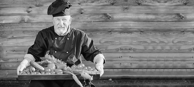 Farmer in uniform with fresh vegetables on a wooden bacground