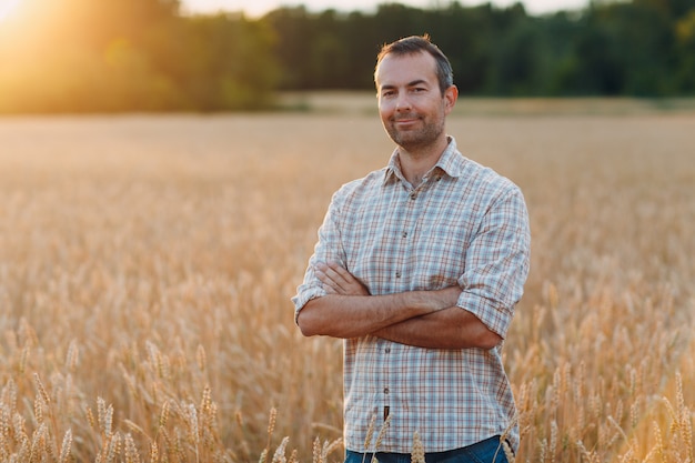 Farmer in wheat field at sunset