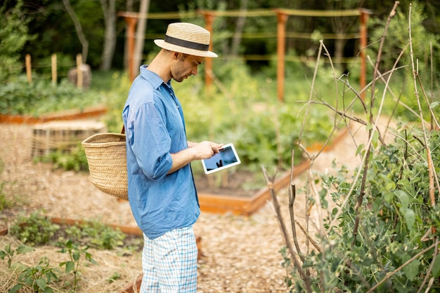 채소밭에서 디지털 태블릿 작업을 하는 농부