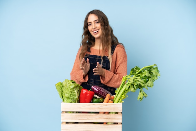 Farmer with freshly picked vegetables in a box applauding after presentation in a conference