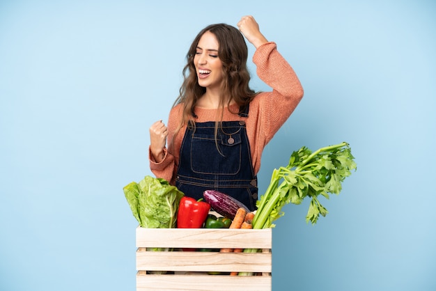 Farmer with freshly picked vegetables in a box celebrating a victory