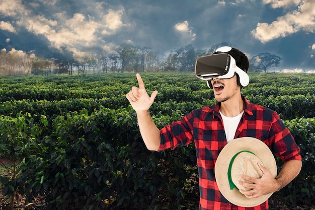 Farmer with hat and virtual reality glasses on coffee plantation landscape concept image