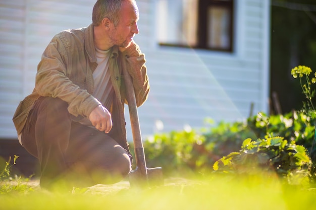 Photo the farmer with a shovel in the garden preparing the soil for planting vegetables gardening concept agricultural work on the plantation