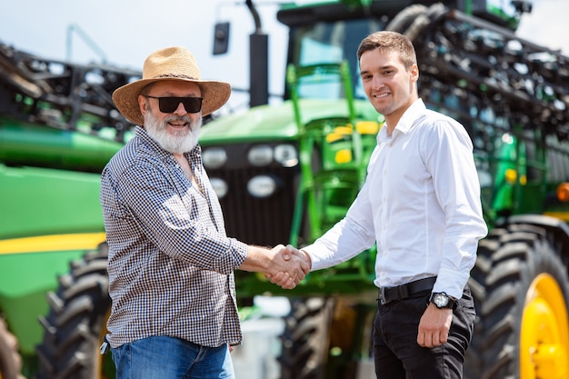 A farmer with a tractor combine at a field in sunlight confident bright colors