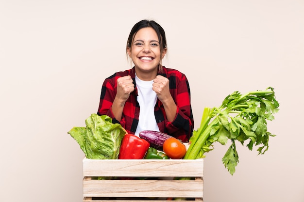 勝利を祝う木製バスケットで新鮮な野菜を保持している農家の女性