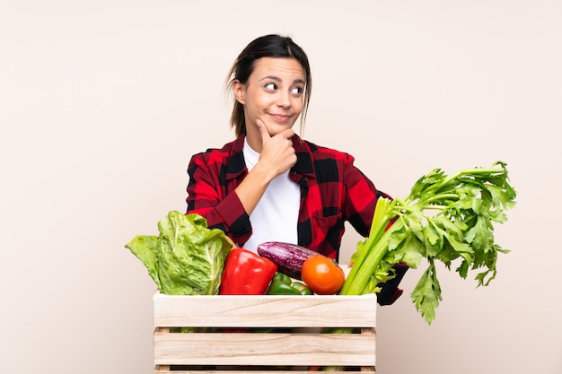 Farmer woman holding fresh vegetables in a wooden basket thinking an idea