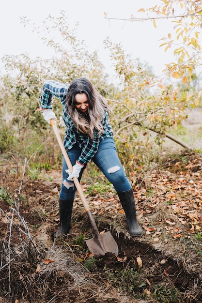 farmer woman using the shovel to make a furrow in the ground