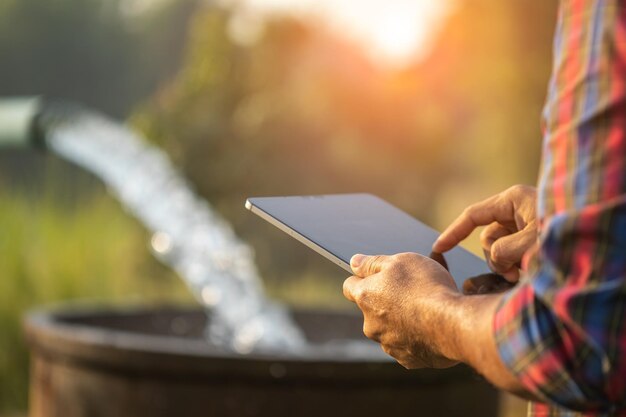 Agricoltore che lavora nel campo di riso uomo che usa la tavoletta digitale per controllare la quantità di acqua da rilasciare nel suo campotecnologia agricola intelligente per il concetto di agricoltura