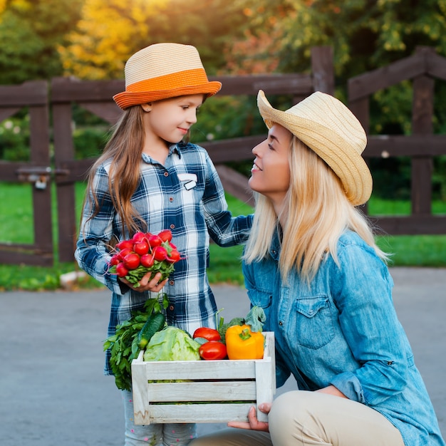 Farmers Mother and child hold a box of vegetables 