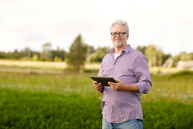 farming, agriculture, technology, old age and people concept - happy senior man with tablet pc computer at county or farm