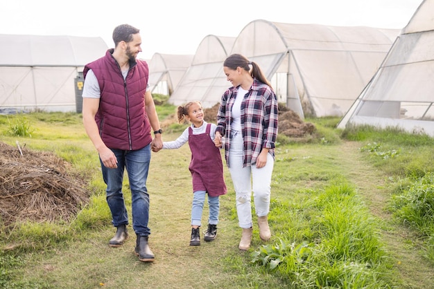 Farming family and sustainable lifestyle with child and parents walking together on a field for love bonding and support in countryside Happy girl man and woman on an agro and agriculture farm