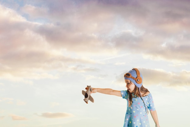 Fascinated girl with a toy airplane in her arms imagining her future profession as a pilot, dreaming and future generation concept