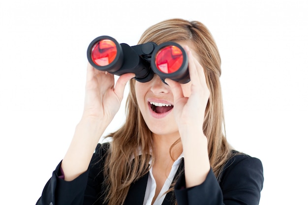 Fascinated young businesswoman looking through a spyglass