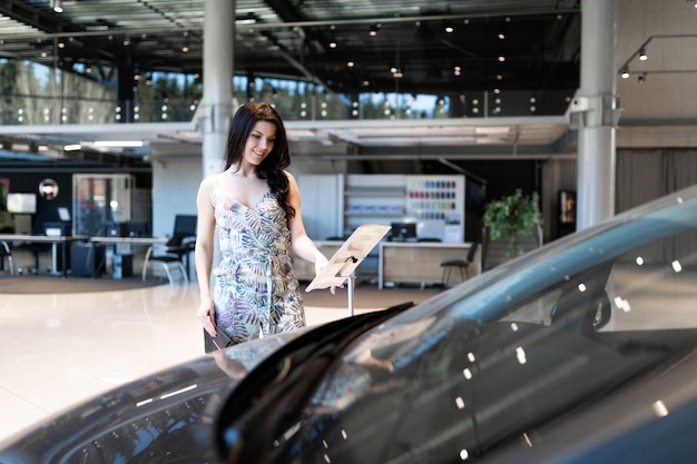 Photo fascinating brunet checking description of new car in dealeship center