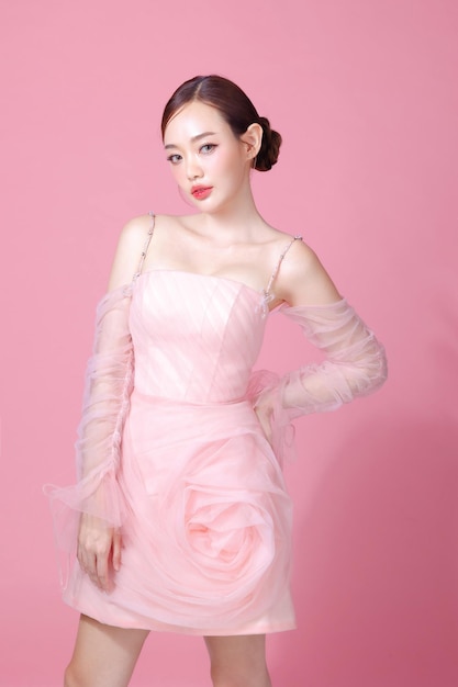 Fascinating fun joyful young woman of Asian wears sweet pink flower dress pose gesture isolated on plain pastel light pink background Beautiful lady portrait in studio