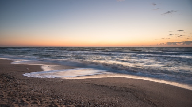 Fascinerende zeegolven spatten langs het zandstrand