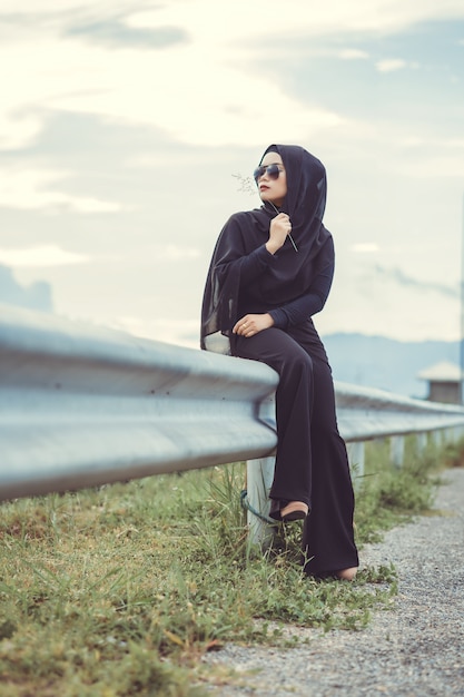 Foto ritratto di fashi di giovane bella donna musulmana con l'hijab nero e il vestito nero completo. stile vintage