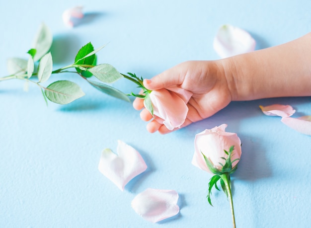 Fashion art  hand of a little child holding flowers on blue background
