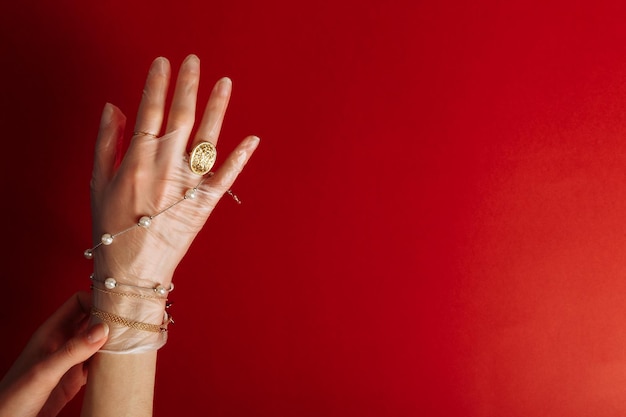 Fashion art hand woman in the glove protection against COVID19 with Jewelry isolated on red background