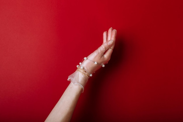 Модная художественная рука женщина в перчатке защищает от COVID19 с украшениями на красном фоне