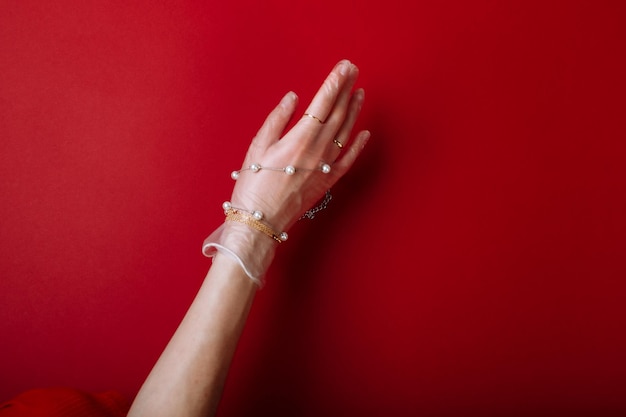 Fashion art hand woman in the glove protection against COVID19 with Jewelry isolated on red background