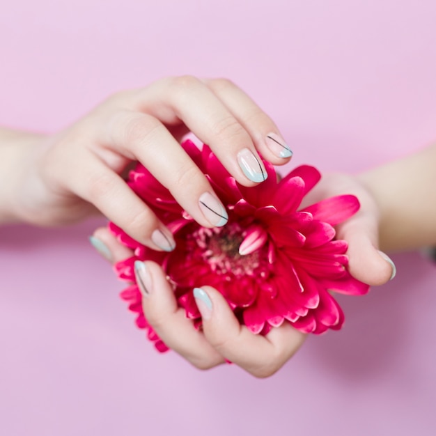 Photo fashion art portrait woman flowers in her hand with a bright contrasting makeup nail. creative beauty photo girl a contrasting pink wall with colored shadows