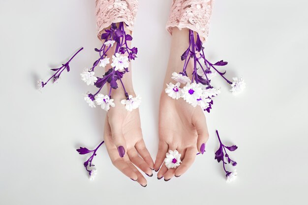 Fashion art woman in summer dress and flowers in her hand with a bright contrasting makeup. Creative beauty photo womans sitting at table