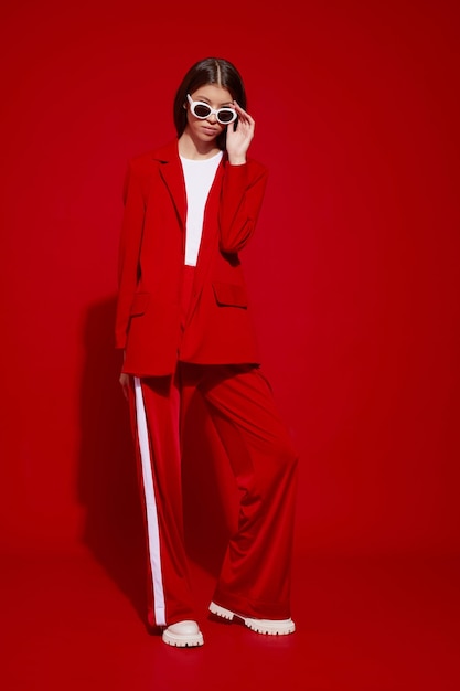 Fashion asian female model in red suit white boots and sunglasses