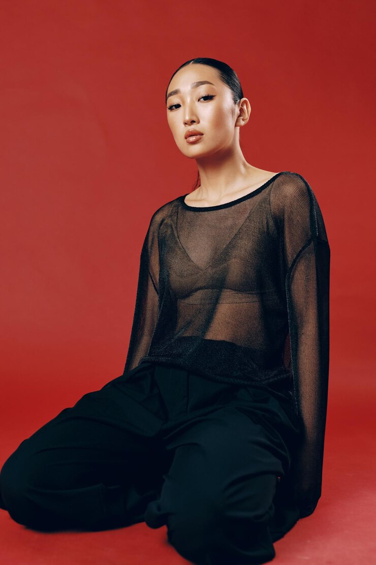 Photo 패션 아시아 여성은 은 바탕에 앉아 눈을 감고 손을 고 바지를 입고 있습니다.