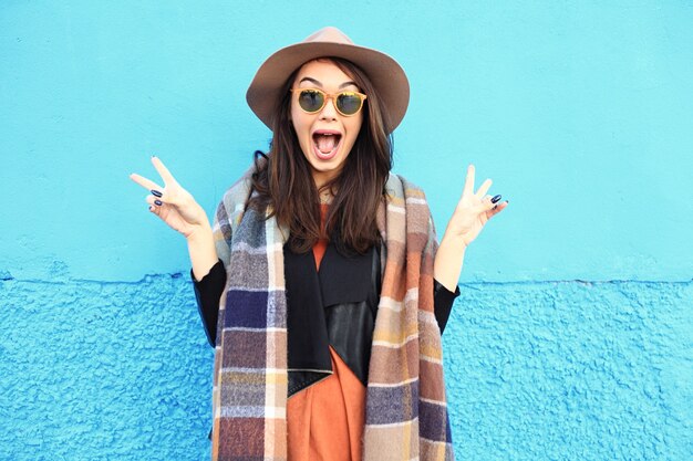 Fashion autumn portrait woman in trendy hat on a blue