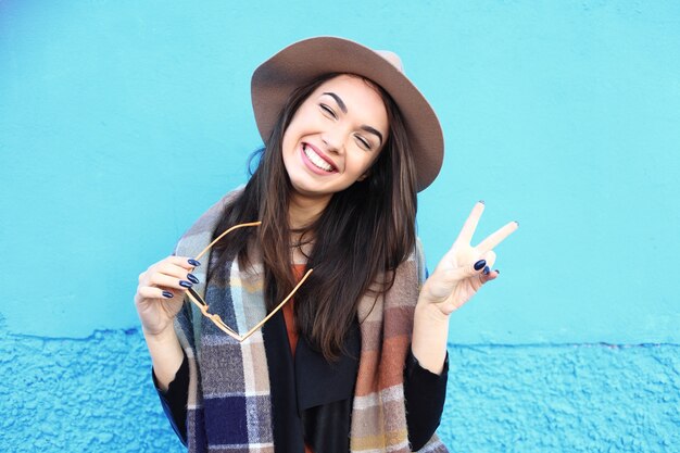 Fashion autumn portrait woman in trendy hat on a blue