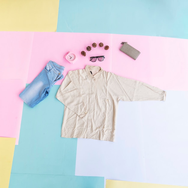 Photo fashion background concept. women's shirt, blue pants, women's bag on multi-colored pastel paper background