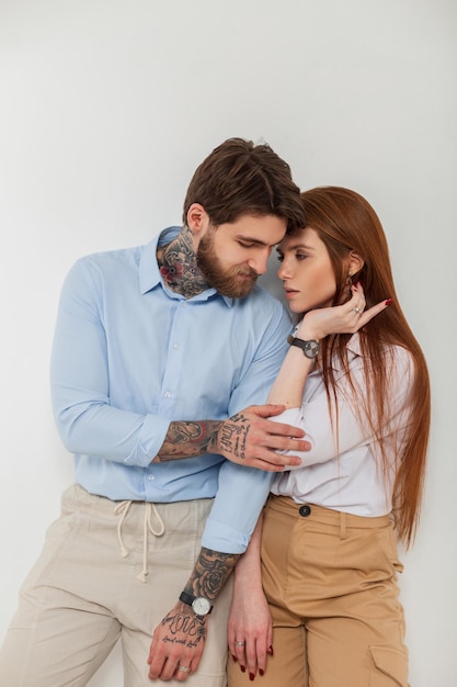 Fashion beautiful couple stylish redhead woman model and handsome hipster man in stylish elegant clothes with shirt in studio on white background