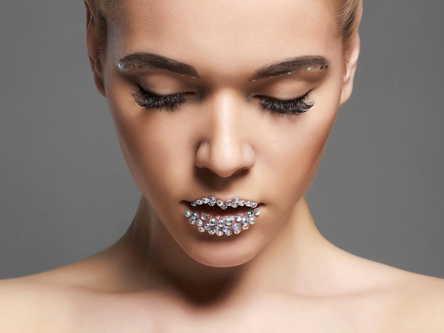 Fashion beautiful woman with crystals on lips