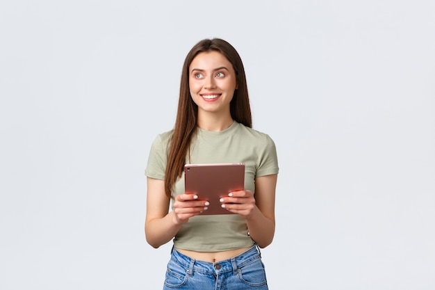 Fashion and beauty, lifestyle and shopping concept. Dreamy attractive, stylish woman looking top left corner with pleased smile while using digital tablet, making online order