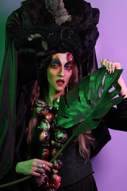 Fashion beauty people and halloween concept Young woman with a bright creative makeup and a big black headdress