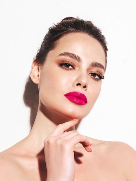 Fashion beauty portrait of young brunette woman with evening stylish makeup and perfect clean skin Sexy model with hair in a bun posing in studio With pink bright natural lips