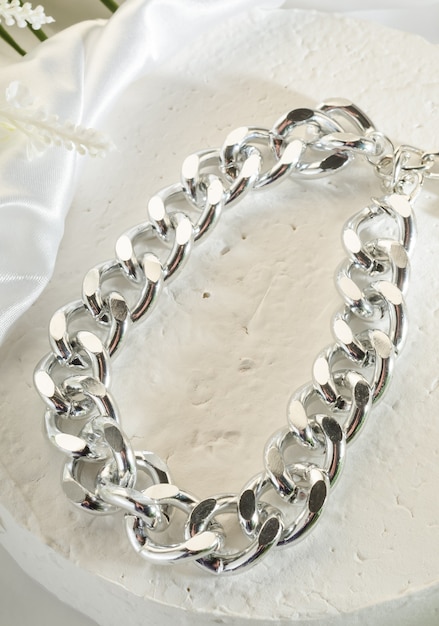 Модная бижутерия - большой серебряный браслет-цепочка на белой подставке крупным планом