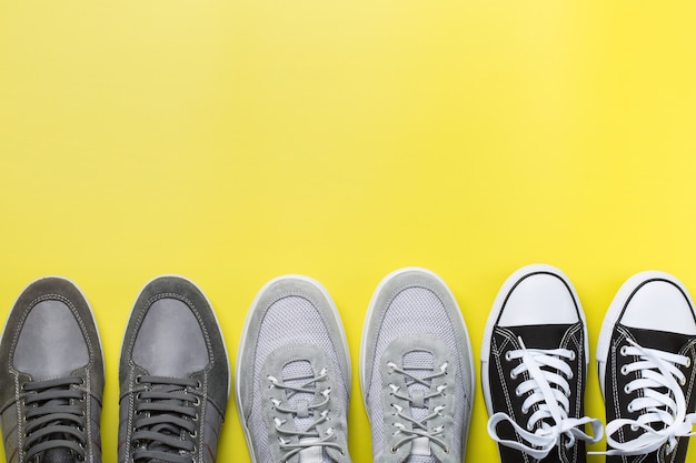 Fashion, blog, blogging, lifestyle, well-being trendy concept. Set of male shoes, sneakers on yellow background, top view, copy space, flat lay