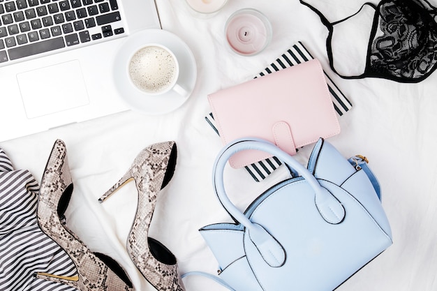 Fashion blogger workspace with laptop and woman accessory in bed. flat lay,  top view