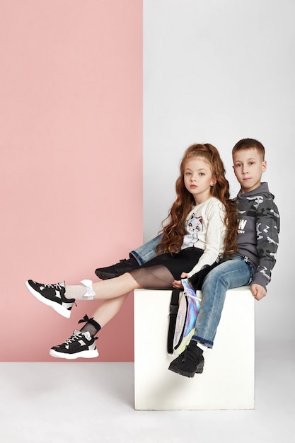 Fashion boy and girl in stylish clothes on colored wall background. Autumn bright clothes on children, a child posing on a colored purple pink background. Russia, Sverdlovsk, 6 April 2019